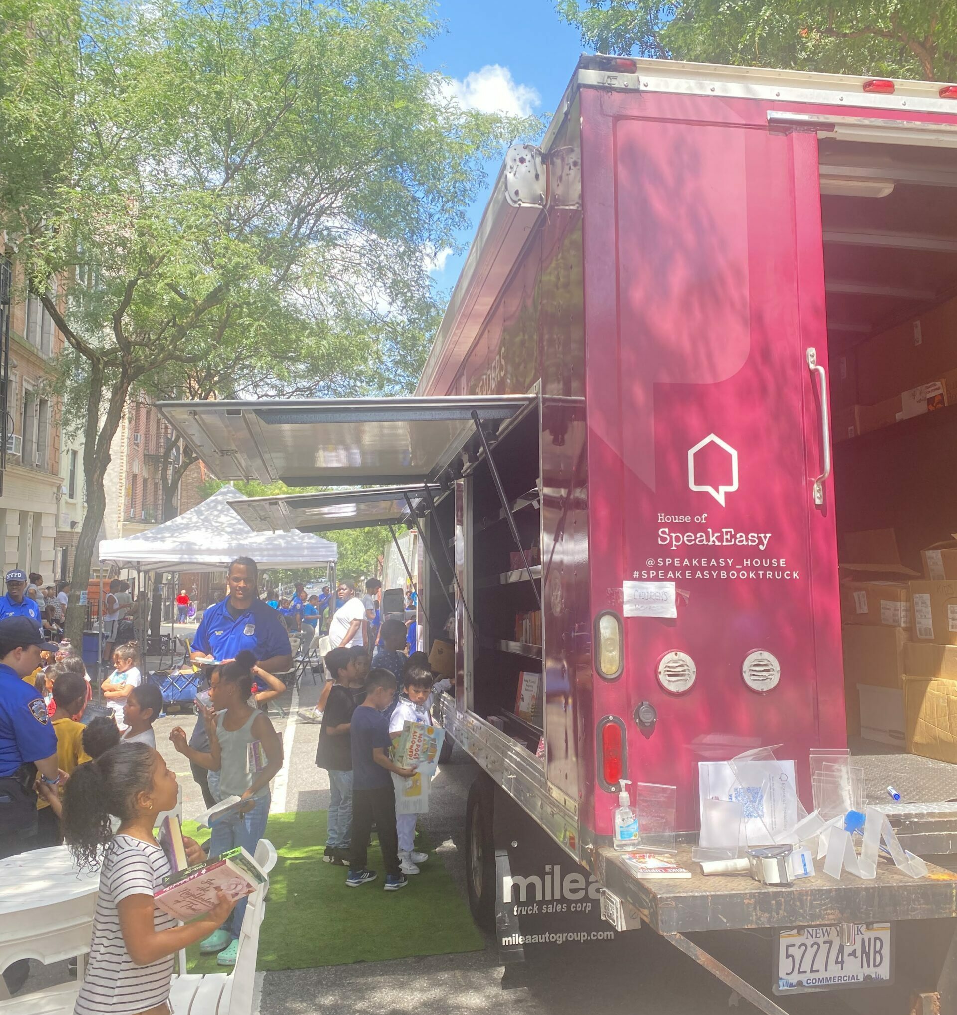 A crowd of young children gathers around House of SpeakEasy's Bookmobile