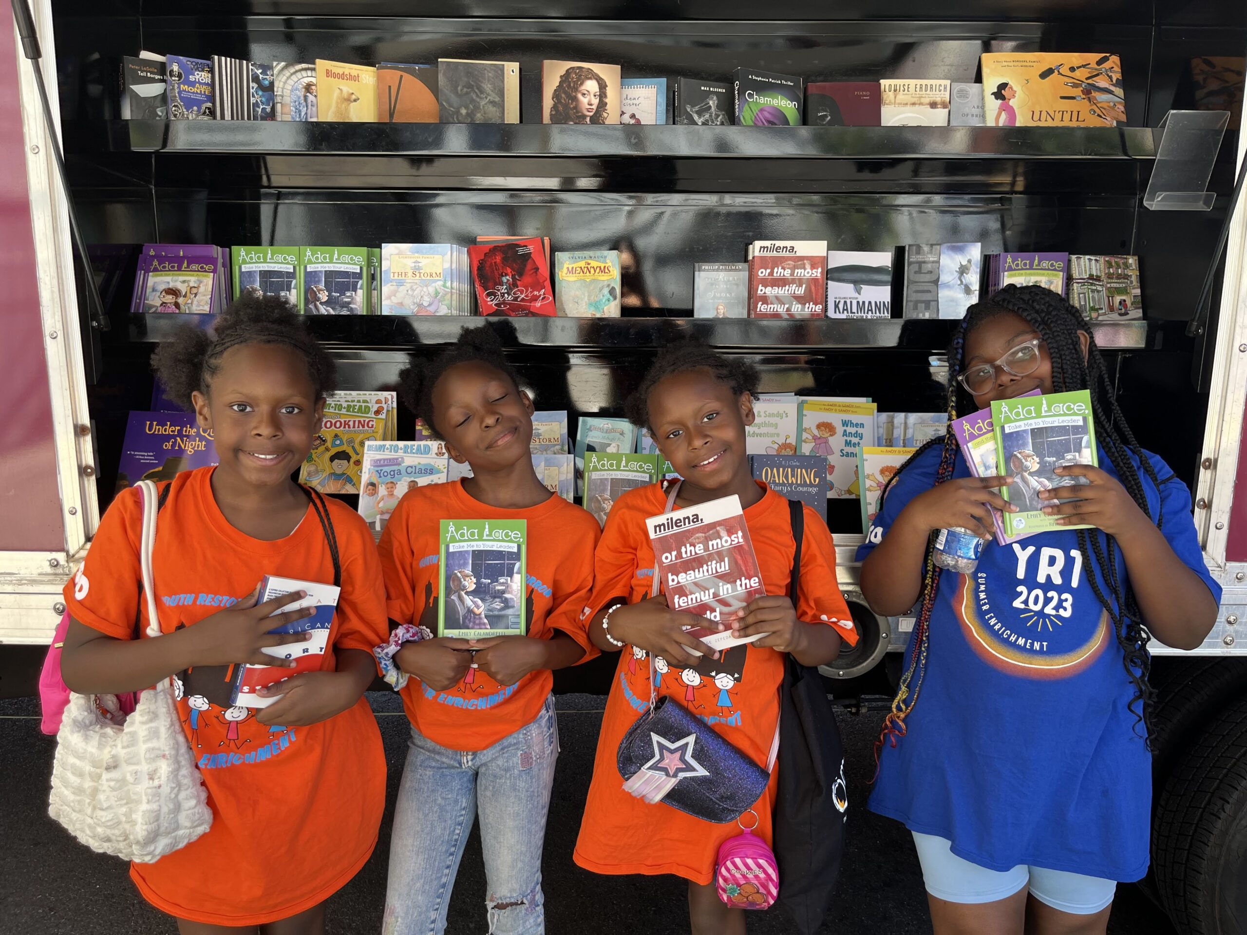 A crowd of young children gathers around House of SpeakEasy's Bookmobile