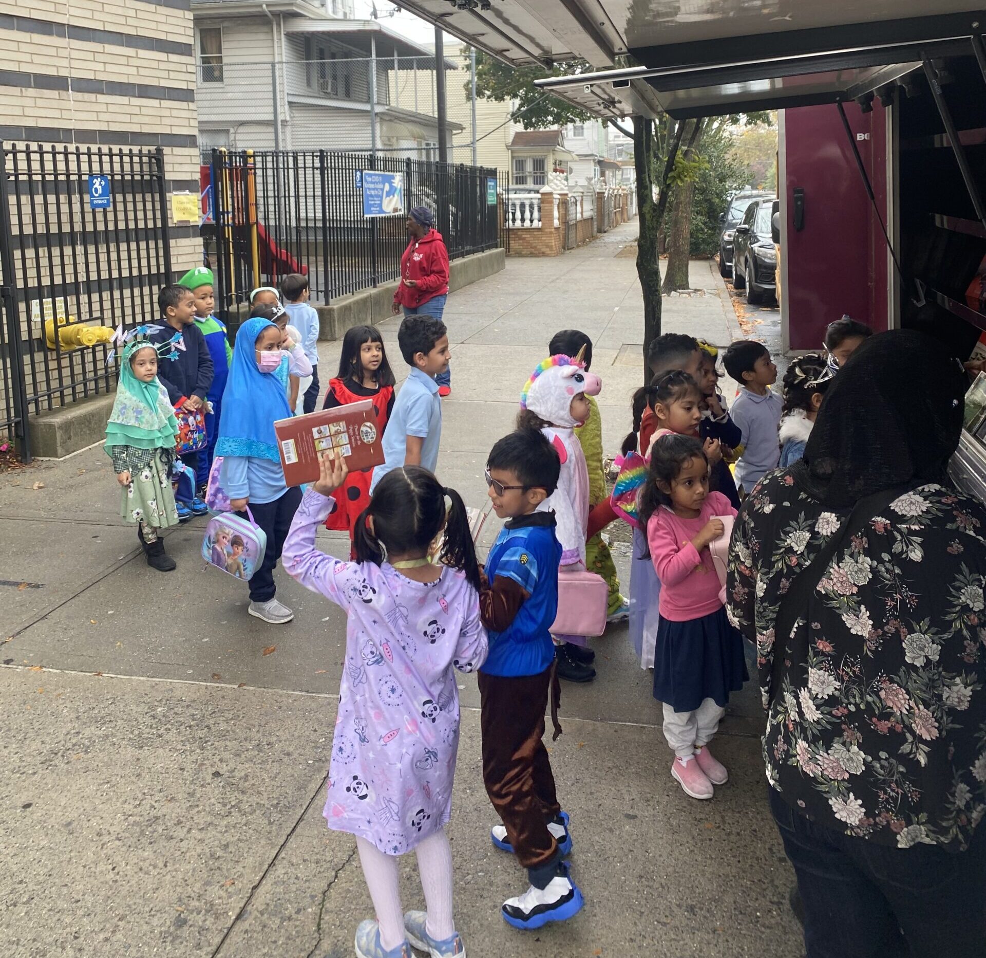 A crowd of young children gathers around House of SpeakEasy's Bookmobile