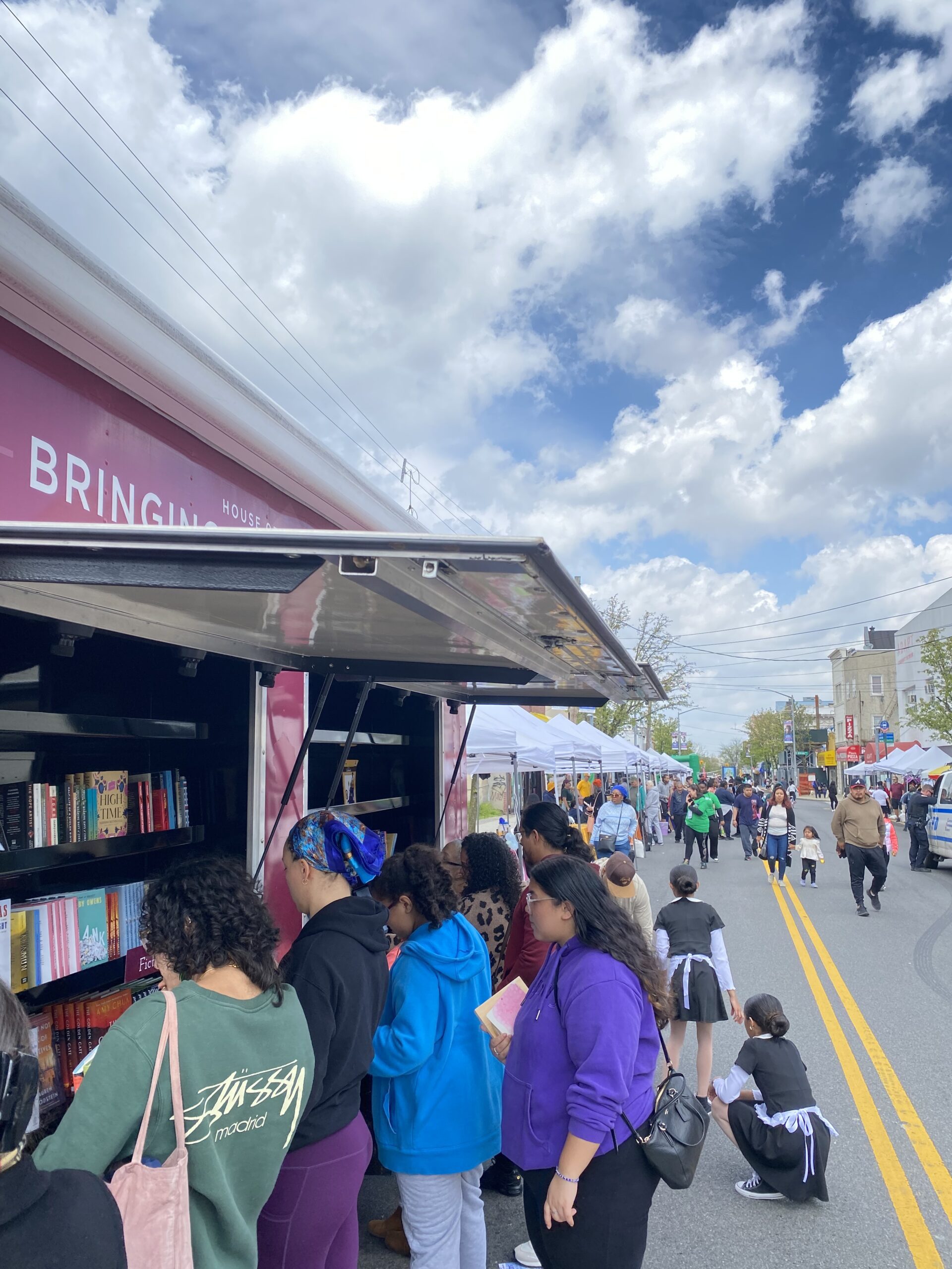 A crowd of young children gathers around House of SpeakEasy's Bookmobile