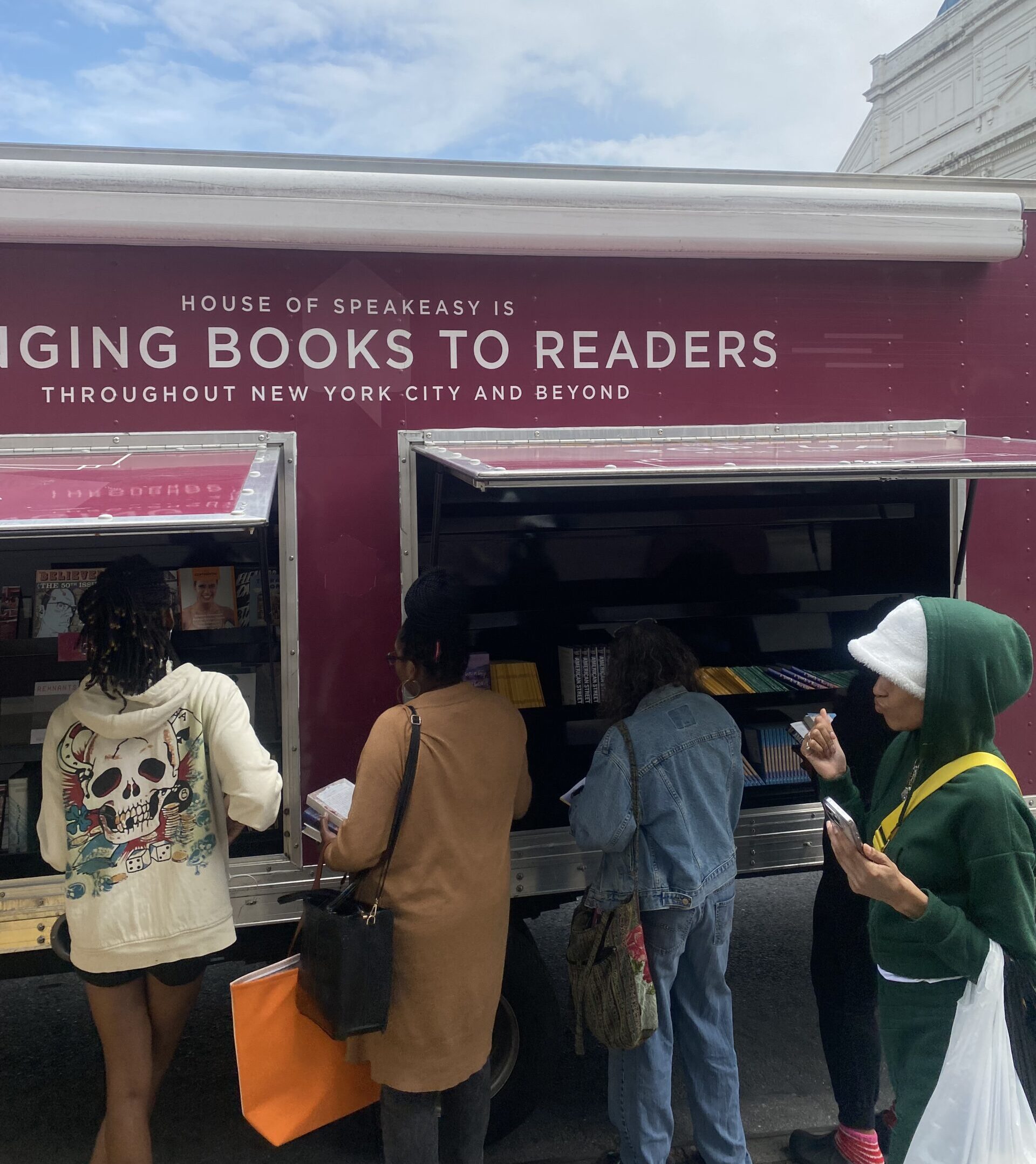 A crowd of young children gathers around House of SpeakEasy's Bookmobile