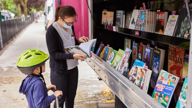 woman and child look at books in a bookmobile