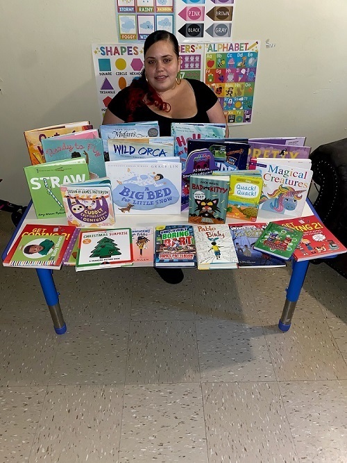 woman seated at a table of picture books